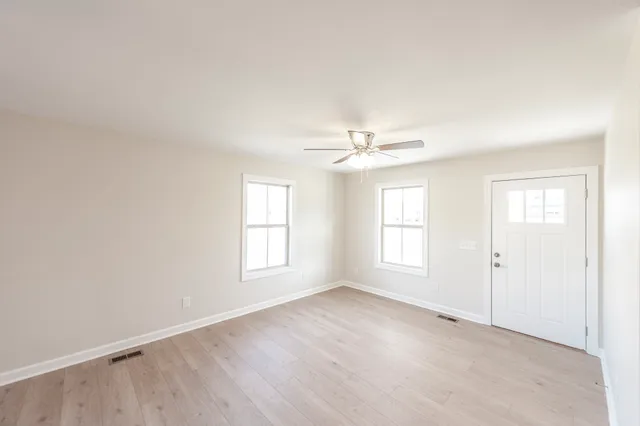 an empty room with windows and chandelier fan
