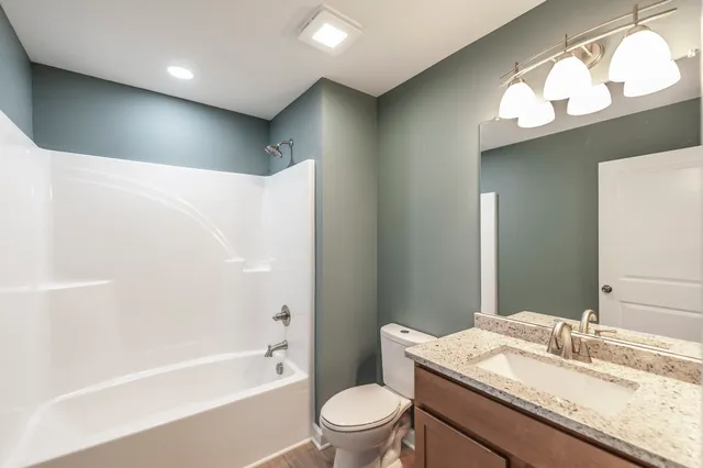 a bathroom with a granite countertop sink a toilet a large mirror and shower