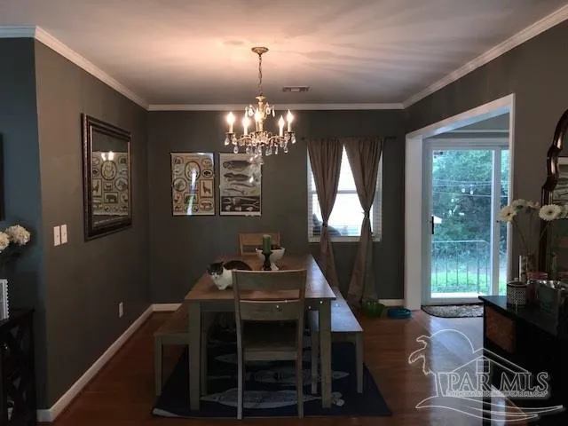 a dining room with wooden floor a chandelier a wooden table and chairs