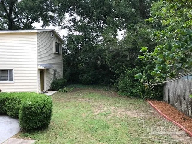 a view of backyard with potted plants and large tree
