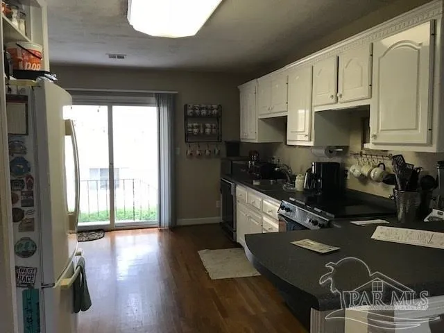 a kitchen with granite countertop a stove a sink dishwasher and a microwave with wooden floor