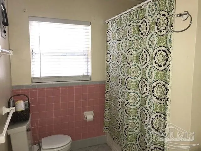 a bathroom with a toilet and a shower curtain