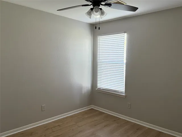 an empty room with a window and a fan
