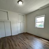 an empty room with wooden floor closet and windows