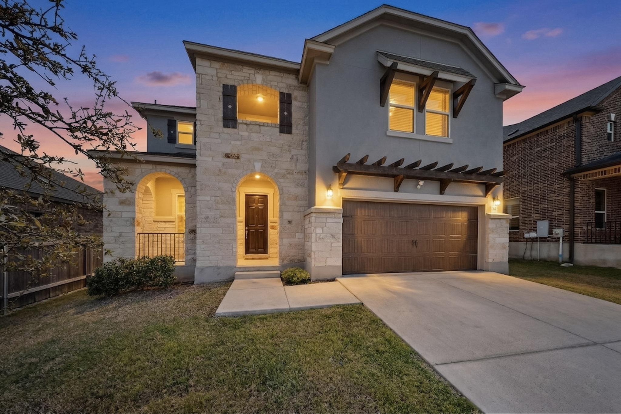 View of front of house with stone siding, stucco siding, driveway, and an attached garage