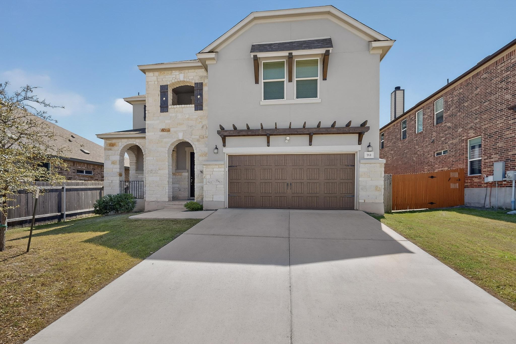 712 Madalin Rue Court Leander, TX 78641 - Photo 2 of 28 View of front of home with stone siding, a garage, concrete driveway, a gate, and stucco siding