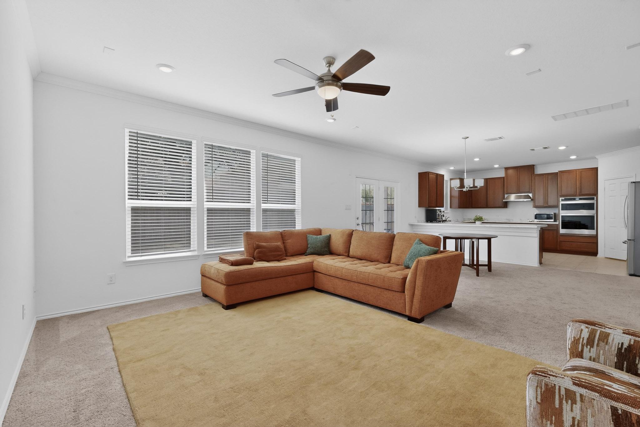 712 Madalin Rue Court Leander, TX 78641 - Photo 6 of 28 Living room with light carpet, a ceiling fan, hanging lights, and crown molding