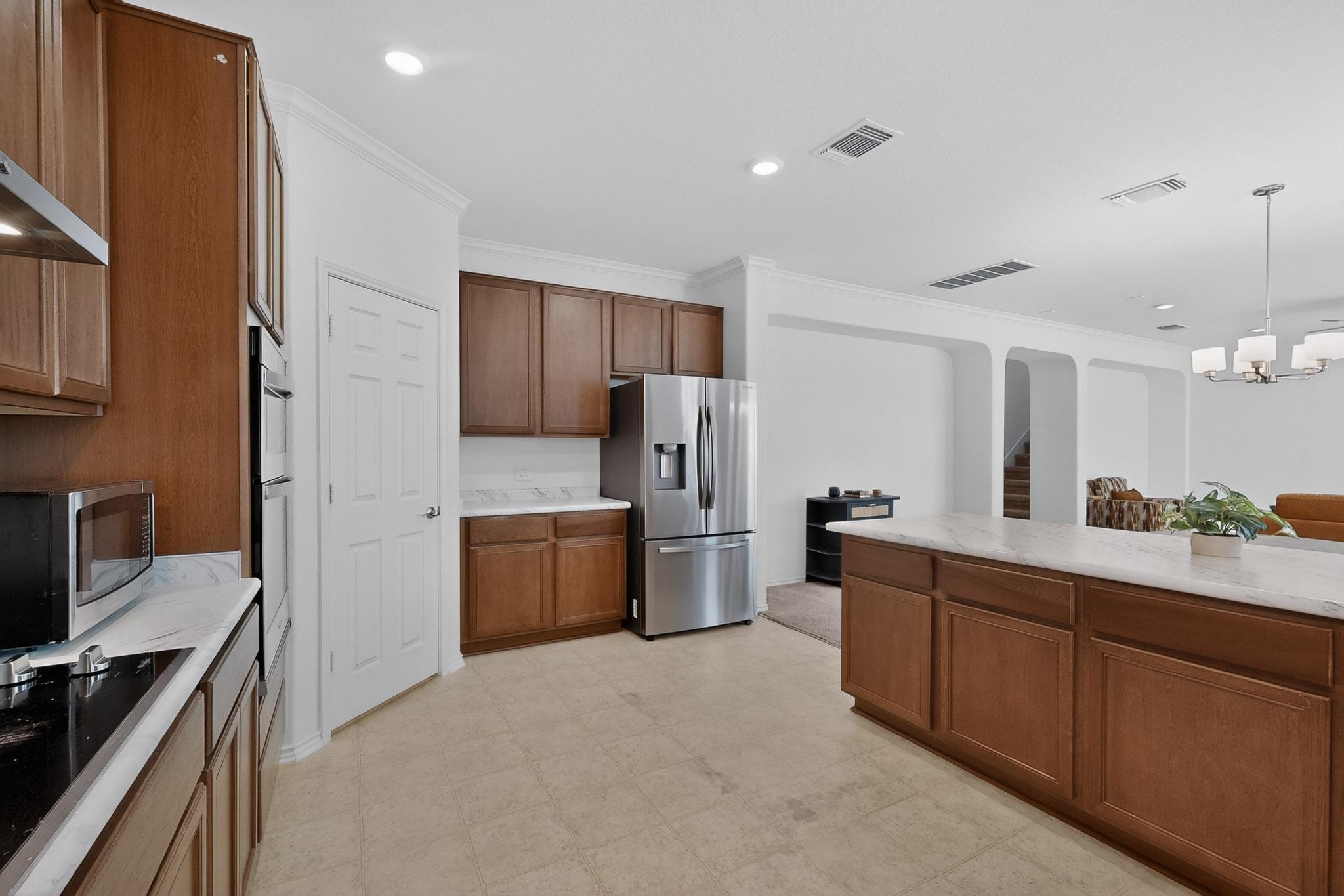 712 Madalin Rue Court Leander, TX 78641 - Photo 9 of 28 Kitchen with stainless steel appliances, wood finish cabinets, light flooring, ornamental molding, and arched walkways