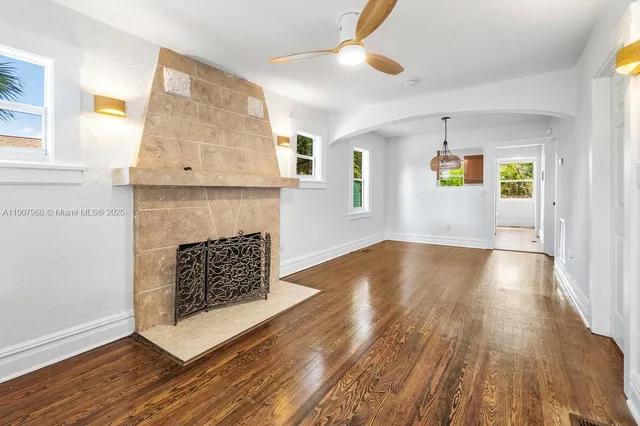 a view of an empty room with wooden floor and a fireplace