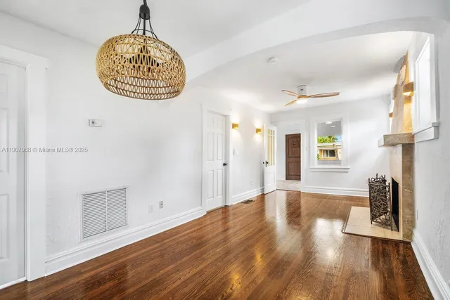 a view of an empty room with wooden floor and windows