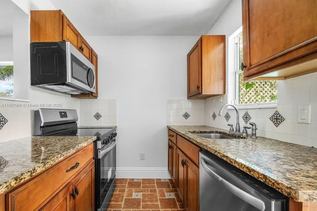 a kitchen with stainless steel appliances granite countertop a sink stove and microwave