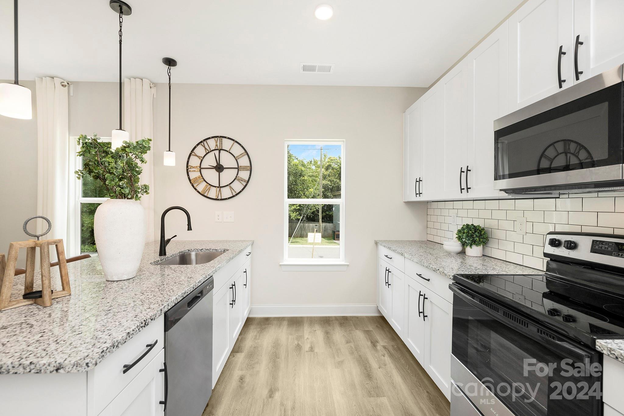 a kitchen with granite countertop stainless steel appliances a stove a sink a window and cabinets