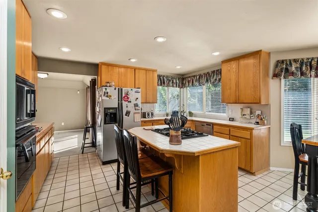 a kitchen with stainless steel appliances granite countertop a sink a stove a refrigerator cabinets and dining table