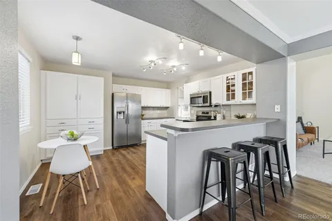 a kitchen with stainless steel appliances kitchen island granite countertop a refrigerator a stove a microwave oven a dining table and chairs with wooden floor