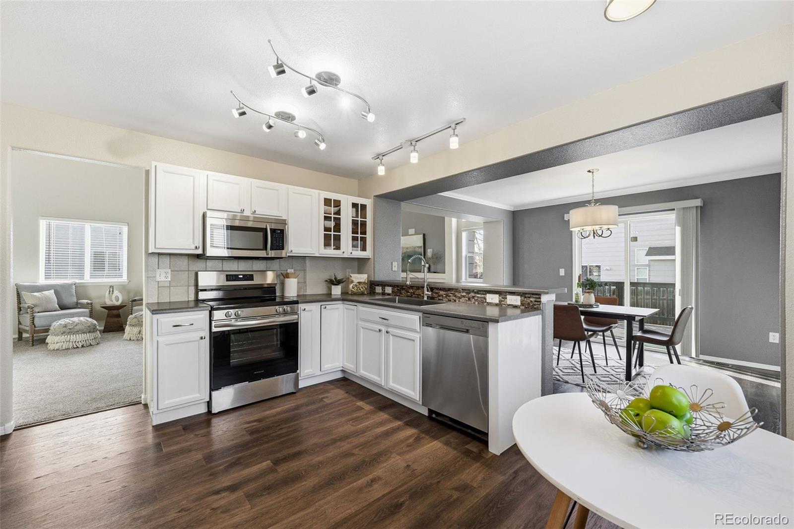 6471 St Vrain Ranch Boulevard Firestone, CO 80504 - Photo 17 of 45 a kitchen with stainless steel appliances granite countertop a stove top oven a sink dishwasher a dining table and chairs with wooden floor