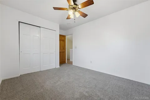 an empty room with closet and a chandelier fan
