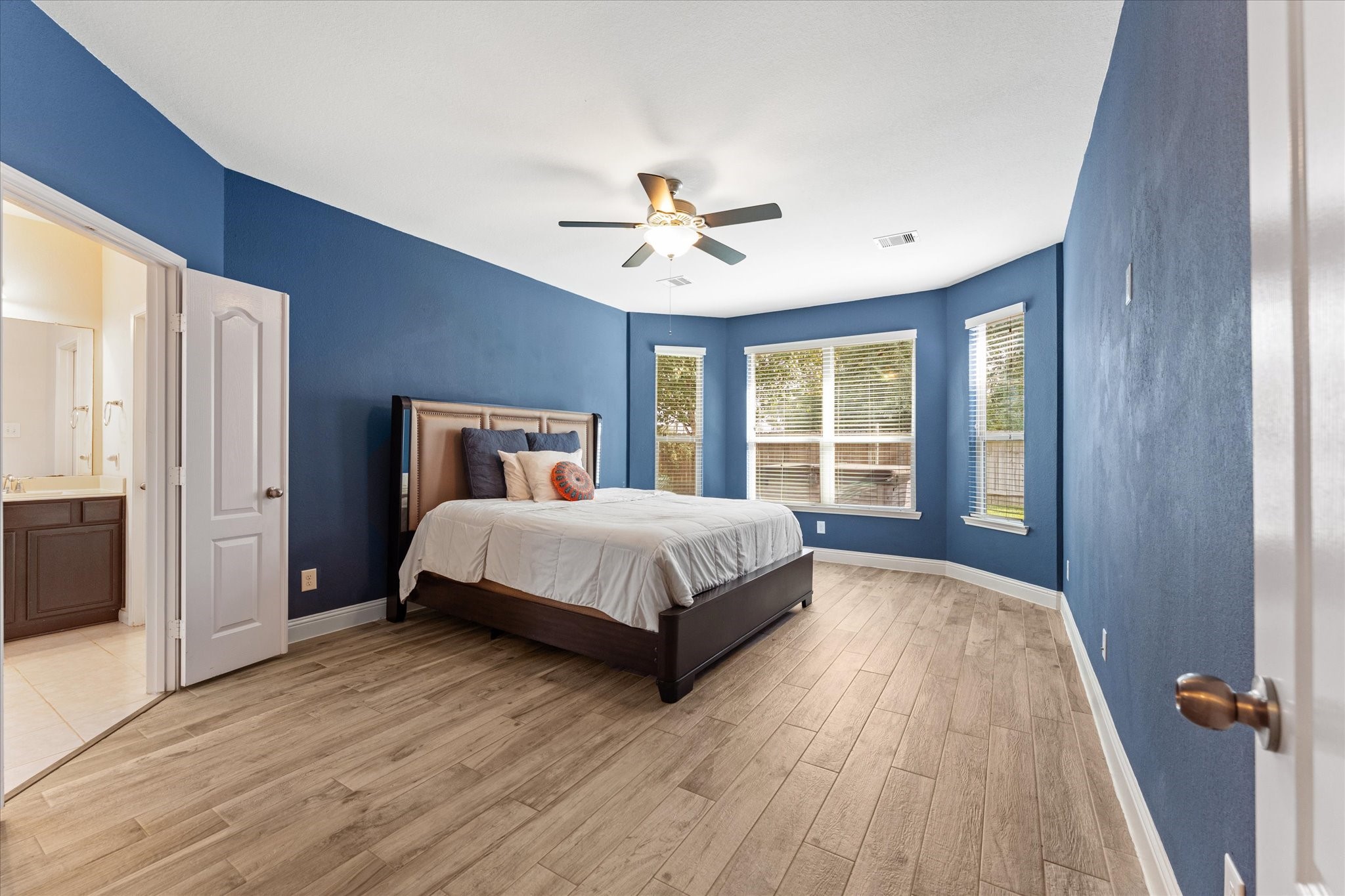3402 Dryer Park Drive Spring, TX 77373 - Photo 18 of 40 Oversized primary bedroom features stylish blue walls and light wood flooring, creating a cozy yet modern ambiance.. The room includes an en -suite bathroom for added convenience.