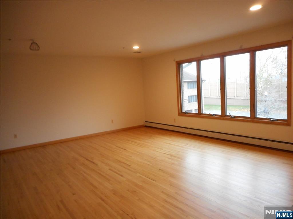 129 River Road, Unit 129 Clifton, NJ 07014 - Photo 4 of 21 a view of an empty room with wooden floor and a window