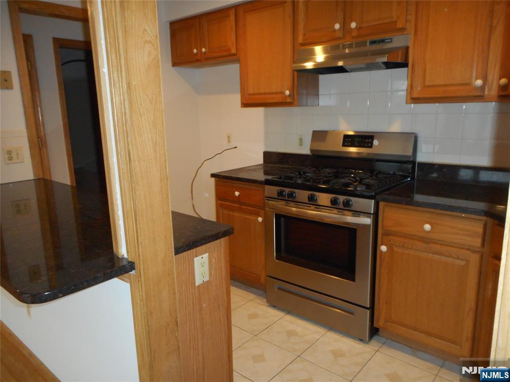 129 River Road, Unit 129 Clifton, NJ 07014 - Photo 8 of 21 a kitchen with stainless steel appliances granite countertop a stove a refrigerator and a microwave