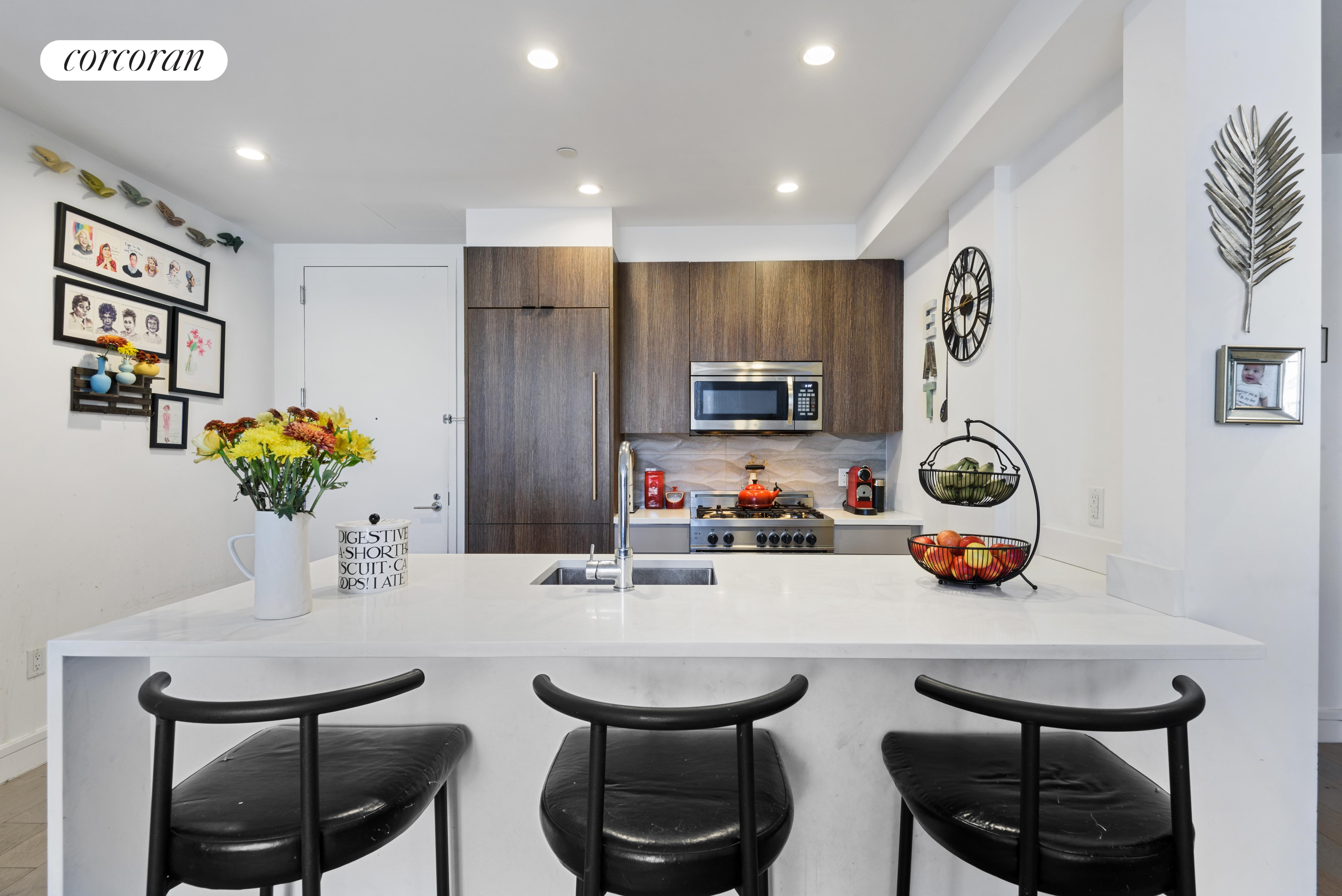 a kitchen with stainless steel appliances a sink a stove a microwave a dining table and chairs