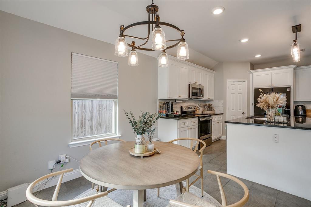 5617 Kilpatrick Avenue Fort Worth, TX 76107 - Photo 20 of 40 a kitchen with kitchen island stainless steel appliances granite countertop a sink a stove a dining table and chairs with wooden floor