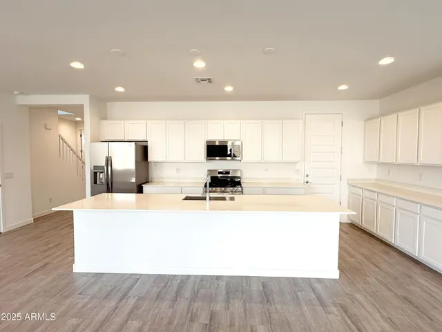 a large kitchen with stainless steel appliances granite countertop a large center island a sink a stove and a refrigerator