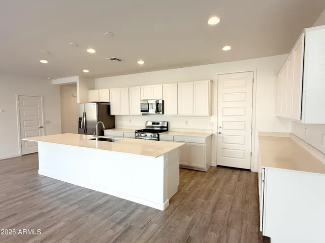 a kitchen with stainless steel appliances a refrigerator sink and white cabinets