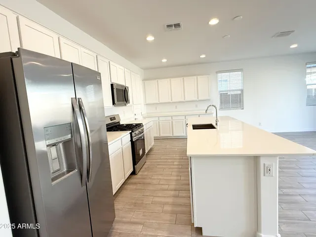 a kitchen with stainless steel appliances a refrigerator sink and white cabinets