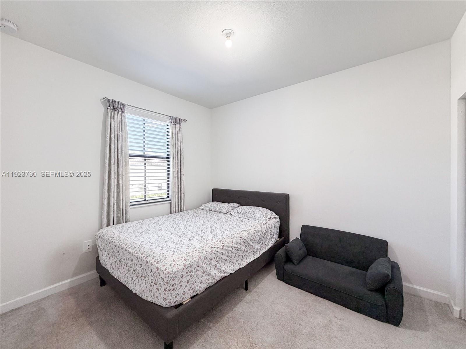 11962 Southwest 247th Terrace, Unit 11962 Homestead, FL 33032 - Photo 21 of 31 a bedroom with a bed couch and a window