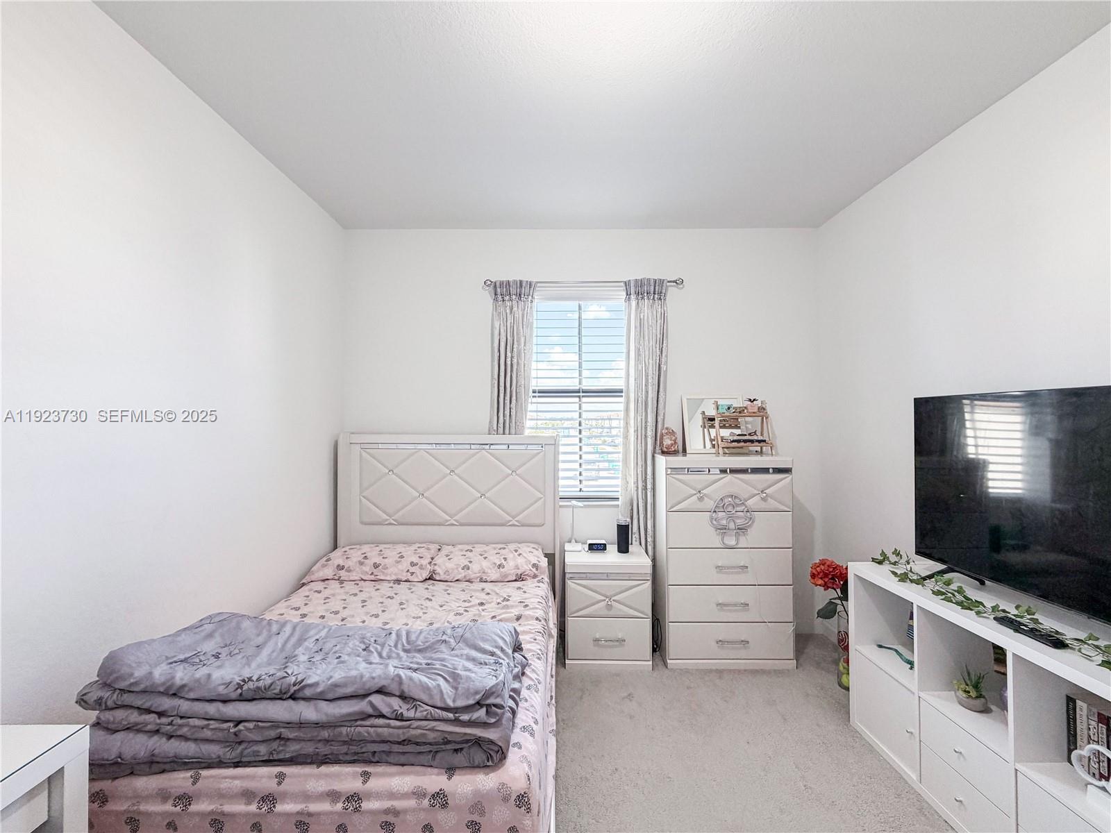 11962 Southwest 247th Terrace, Unit 11962 Homestead, FL 33032 - Photo 24 of 31 a bedroom with a bed and flat screen tv