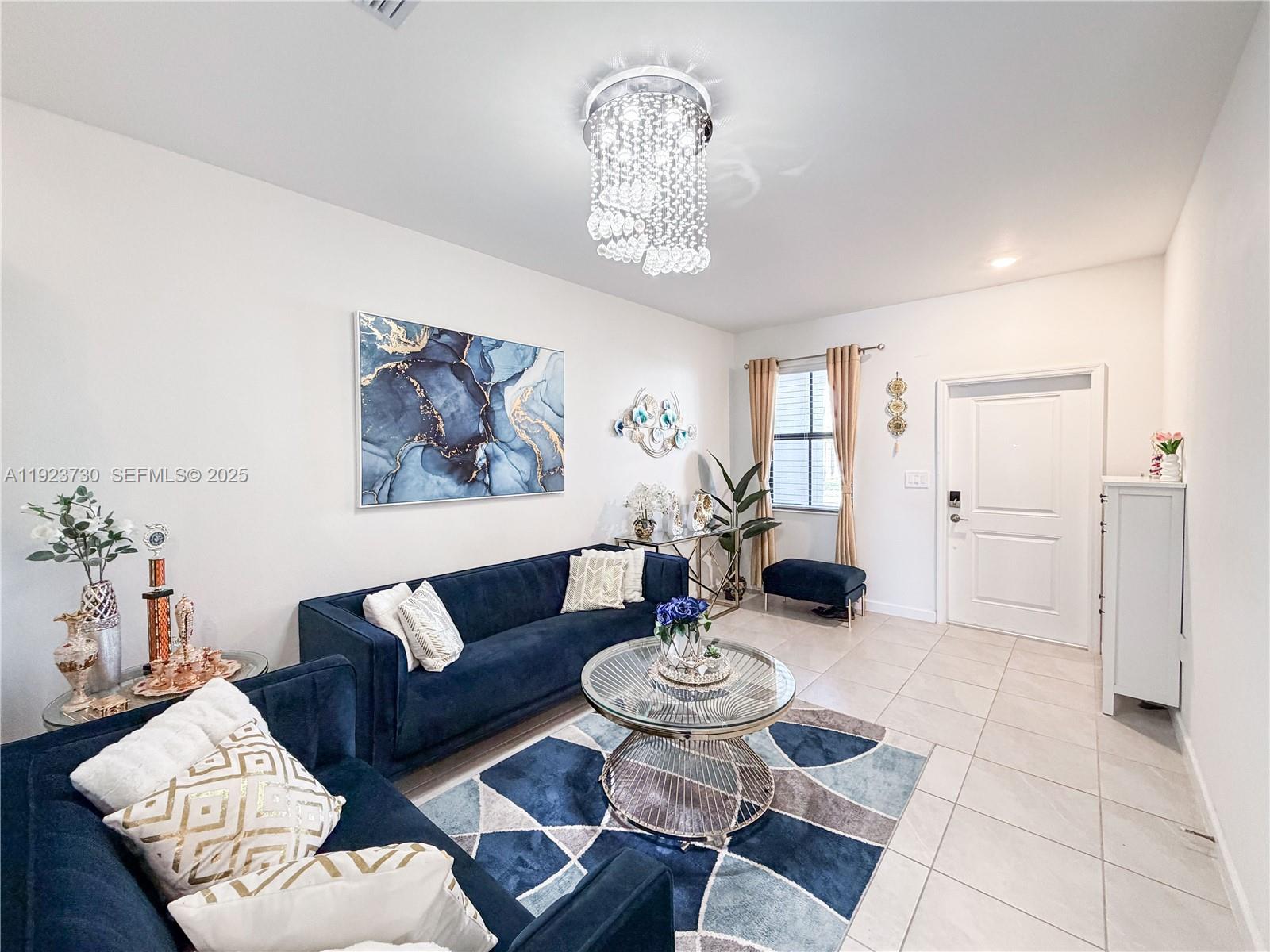 11962 Southwest 247th Terrace, Unit 11962 Homestead, FL 33032 - Photo 4 of 31 a living room with furniture and a chandelier