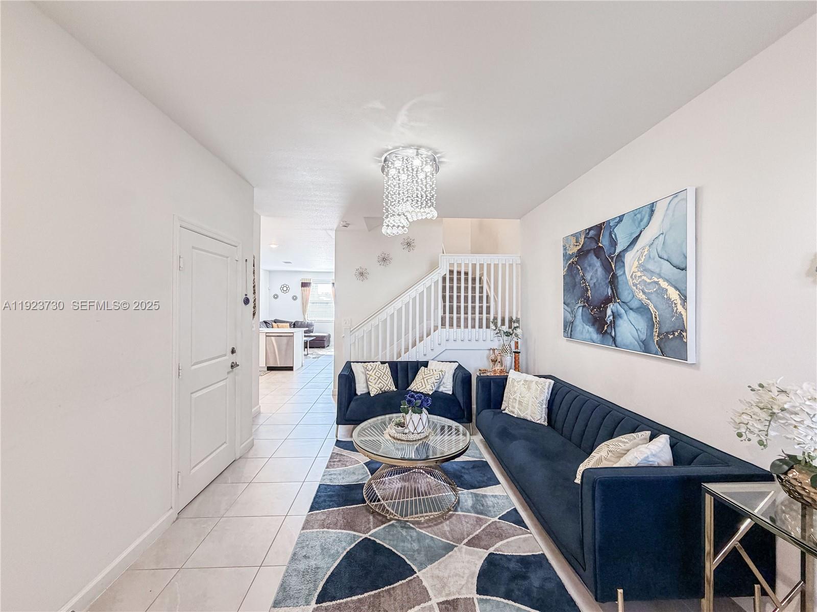 11962 Southwest 247th Terrace, Unit 11962 Homestead, FL 33032 - Photo 5 of 31 a living room with furniture and a chandelier