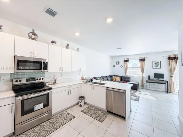a kitchen with stainless steel appliances kitchen island granite countertop a refrigerator and a sink