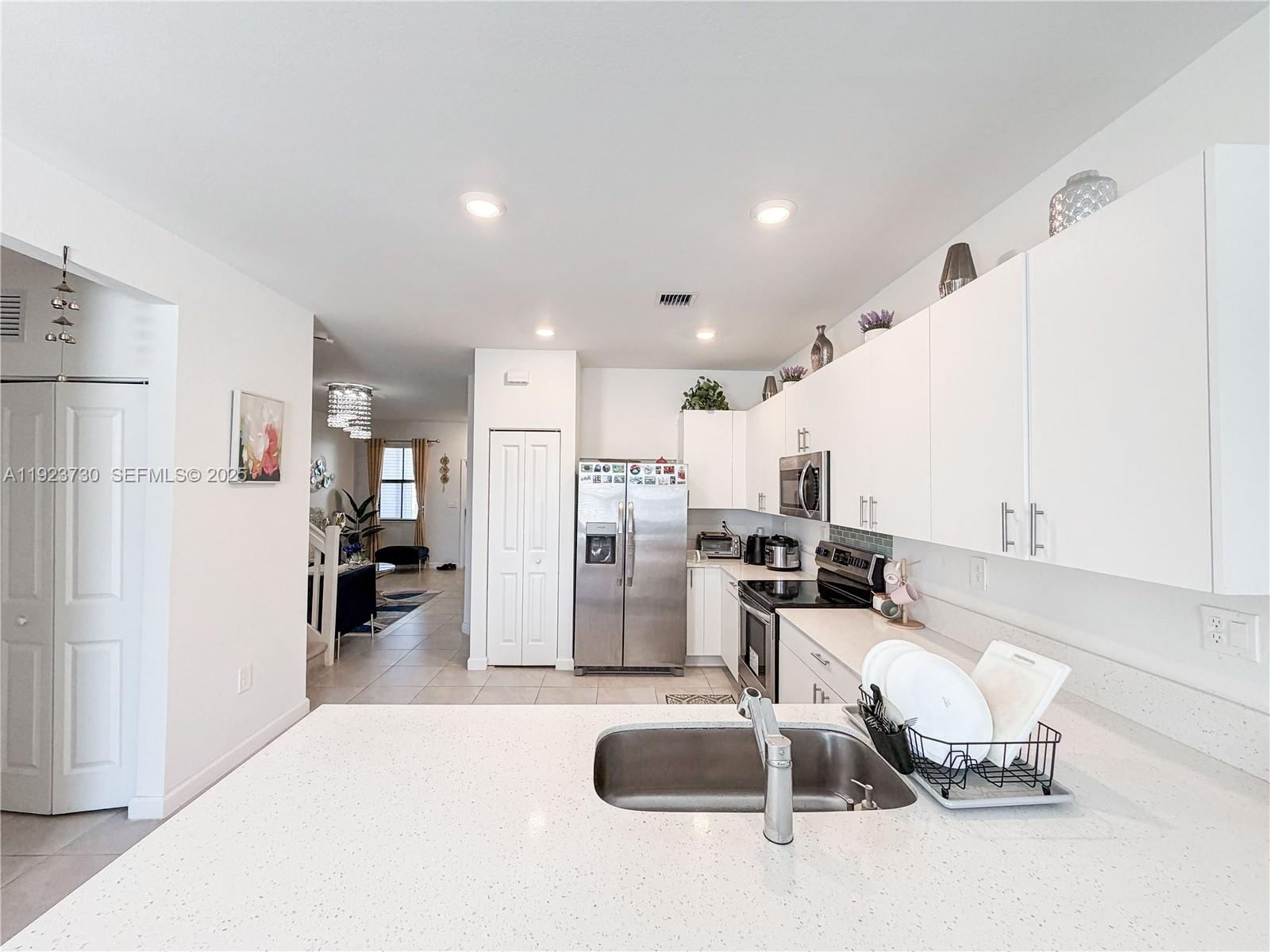 11962 Southwest 247th Terrace, Unit 11962 Homestead, FL 33032 - Photo 10 of 31 a kitchen with kitchen island stainless steel appliances a refrigerator sink and stove