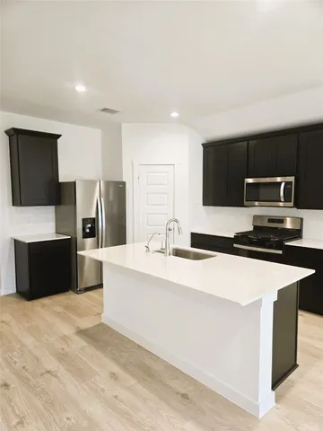 a large white kitchen with stainless steel appliances kitchen island a stove a refrigerator a sink dishwasher with a microwave oven and cabinets