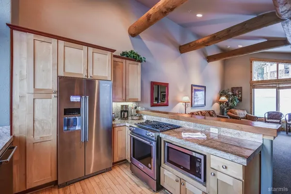 a large kitchen with granite countertop a stove oven and a dining table with the view of living room