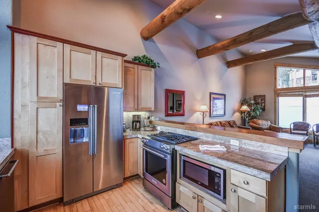 a large kitchen with granite countertop a stove oven and a dining table with the view of living room