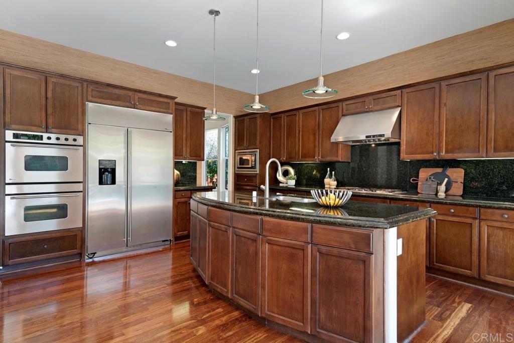 5473 Valerio Trail San Diego, CA 92130 - Photo 11 of 39 a kitchen with kitchen island granite countertop a sink stainless steel appliances and cabinets
