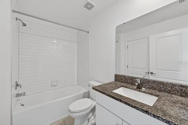 a bathroom with a granite countertop sink a toilet and bathtub