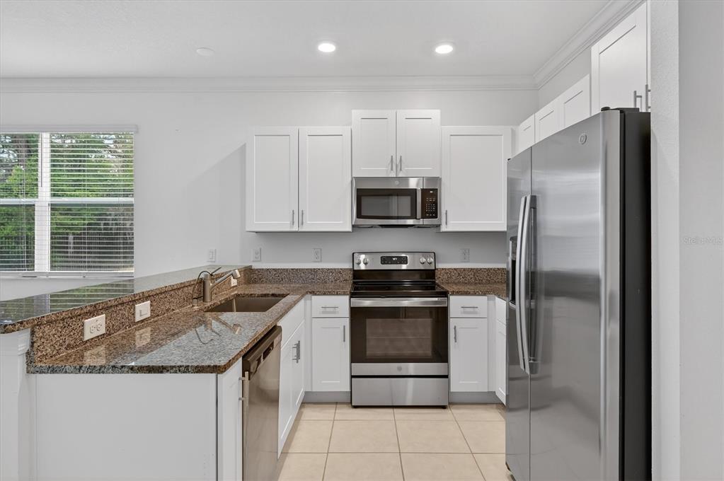 6956 Ripple Pond Loop Zephyrhills, FL 33541 - Photo 4 of 30 a kitchen with stainless steel appliances granite countertop a refrigerator and a sink