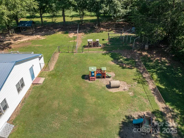 an aerial view of a house with a yard and large trees