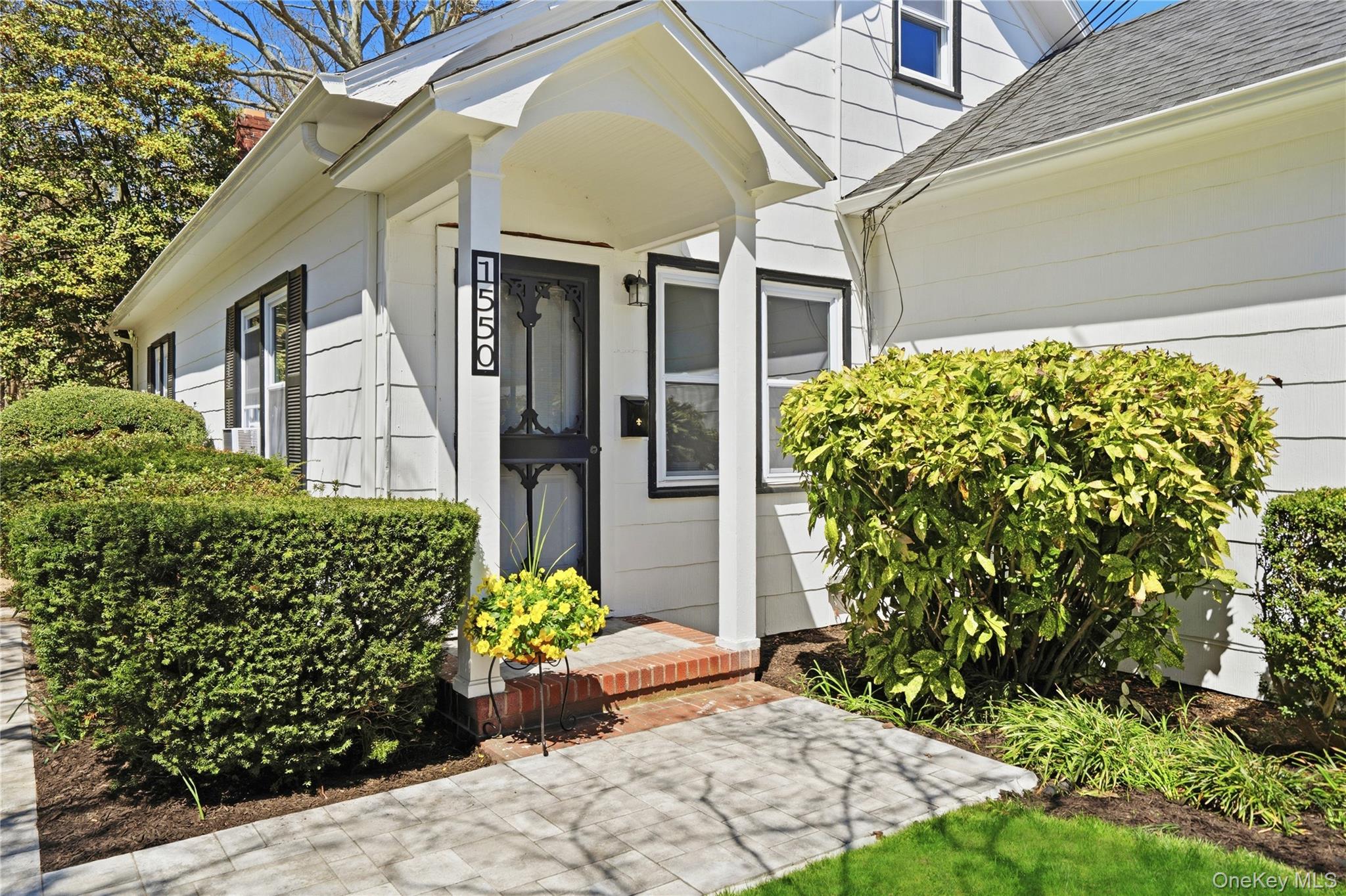 1550 Main Road Riverhead, NY 11901 - Photo 2 of 28 White siding exterior with black trim windows, a covered front entry, and a decorative screen door