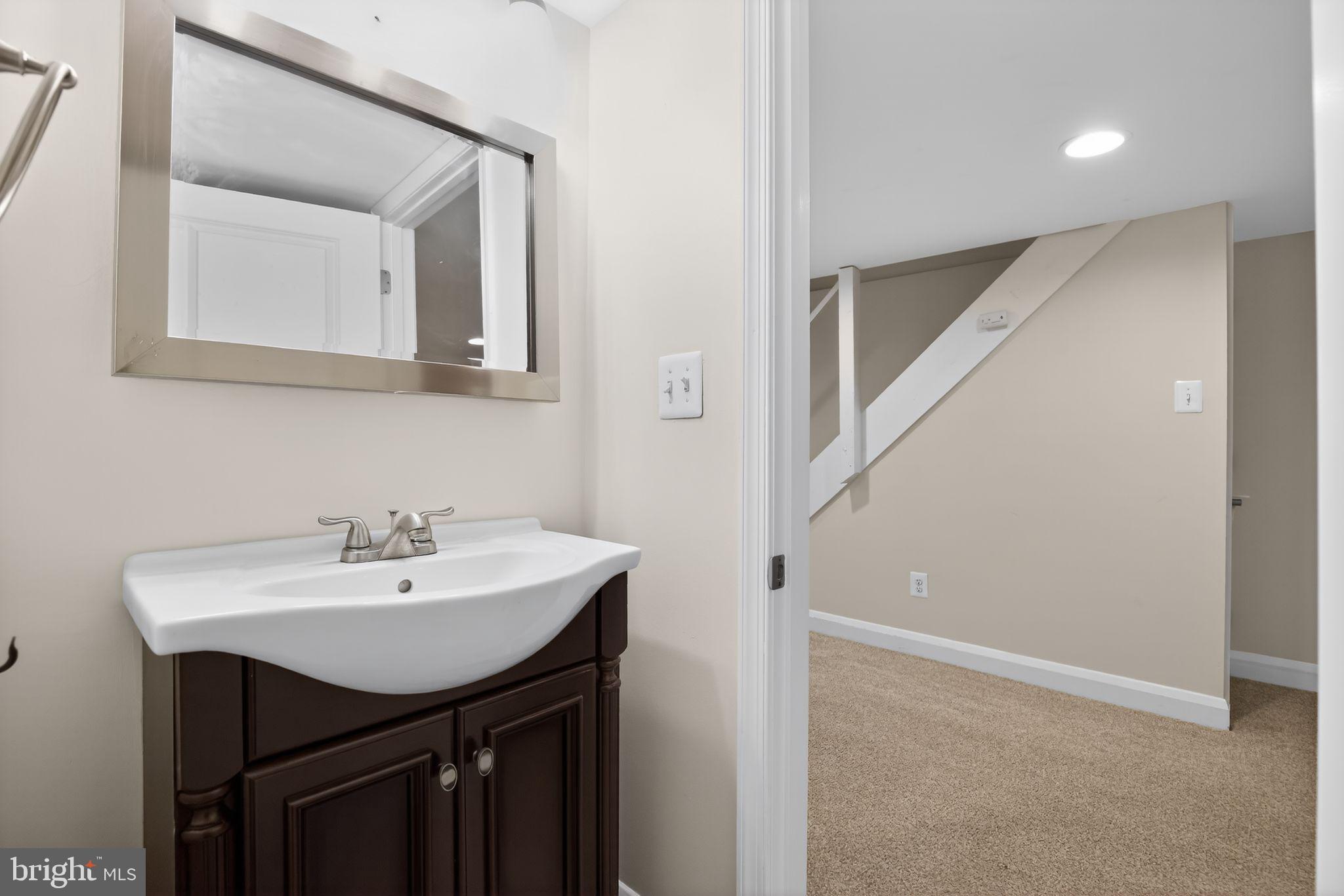 6843 Dunbar Road Baltimore, MD 21222 - Photo 23 of 27 a bathroom with a sink a mirror and vanity