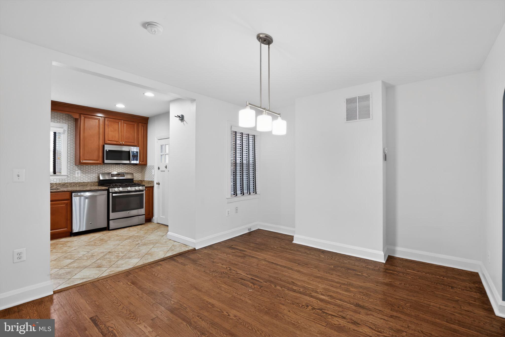 6843 Dunbar Road Baltimore, MD 21222 - Photo 8 of 27 a kitchen with stainless steel appliances granite countertop a refrigerator a stove a sink and a wooden floor
