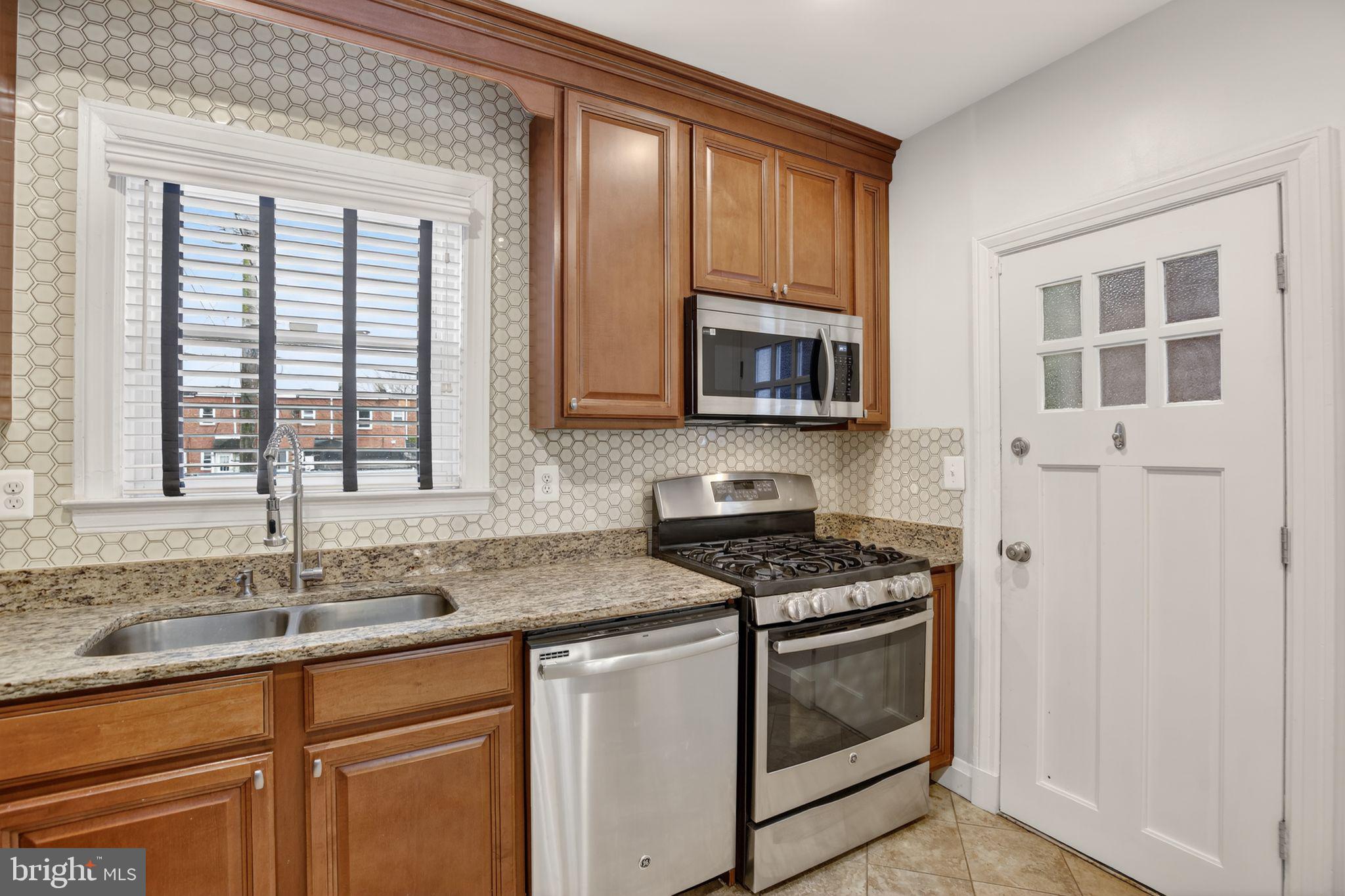 6843 Dunbar Road Baltimore, MD 21222 - Photo 9 of 27 a kitchen with granite countertop a sink stove and microwave