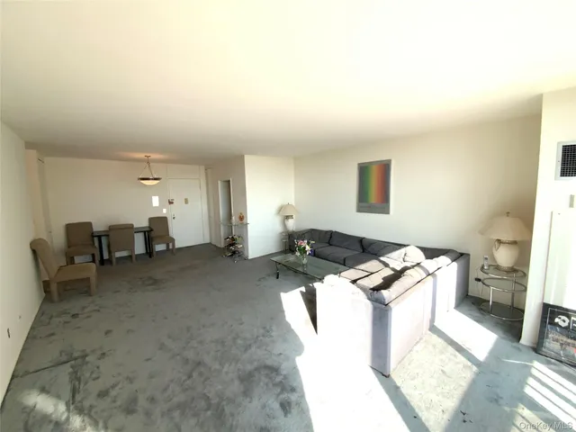 a living room with stainless steel appliances furniture a rug and a window