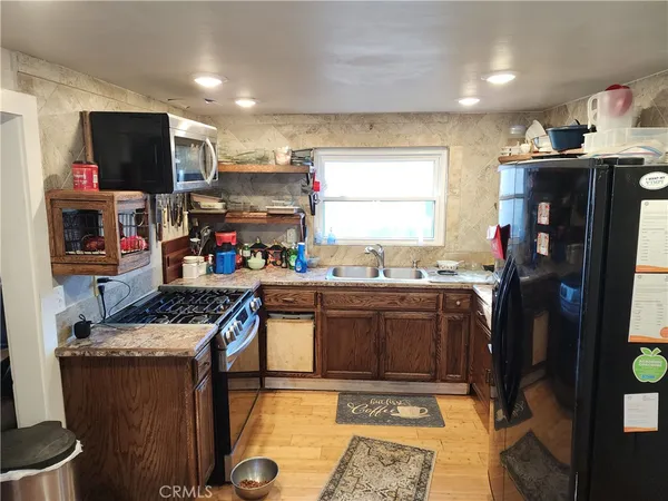 a kitchen with stainless steel appliances granite countertop a stove top oven a sink dishwasher and a microwave with wooden floor