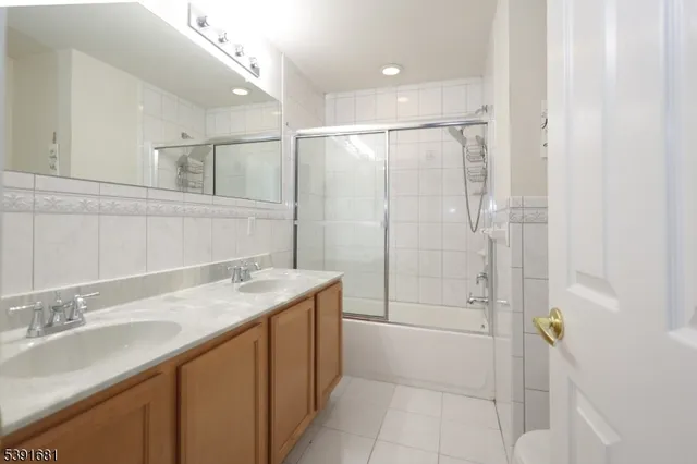 a bathroom with a granite countertop sink a mirror and shower