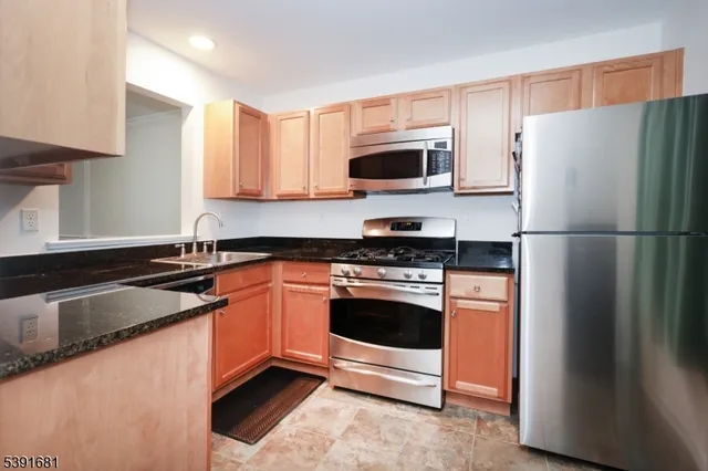 a kitchen with stainless steel appliances granite countertop a refrigerator stove a sink and a microwave