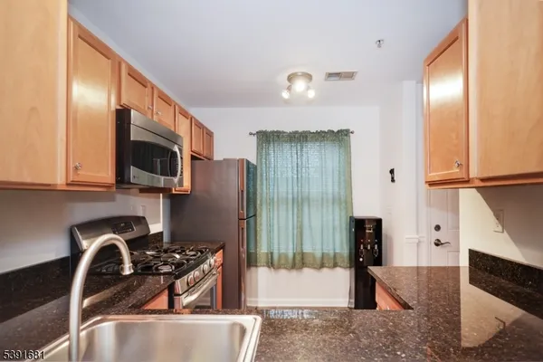 a kitchen with stainless steel appliances granite countertop a refrigerator and a sink